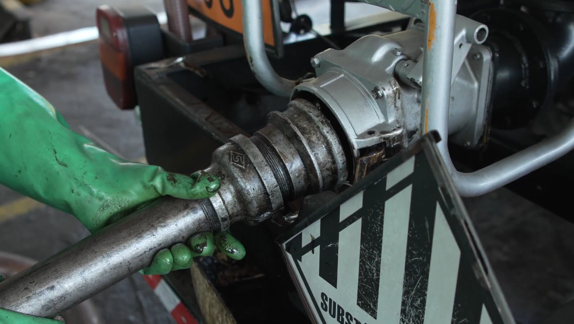 Técnico com EPI coletando óleo lubrificante usado em ambiente industrial